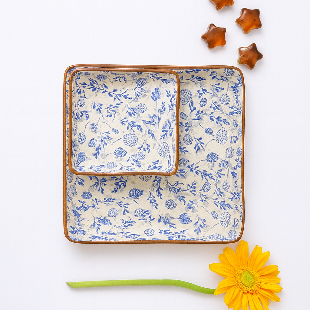 Set of square ceramic plates with floral pattern on a white background, accompanied by a yellow flower.