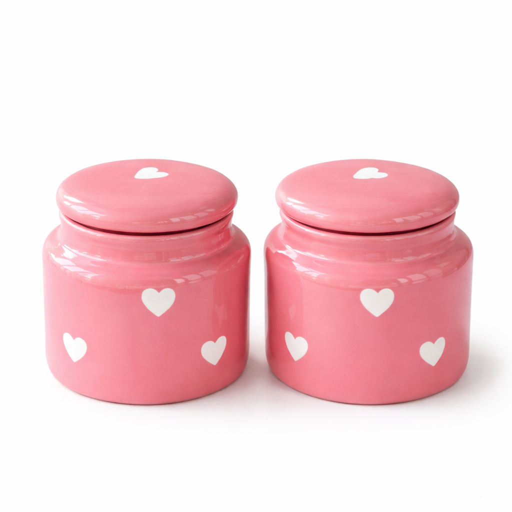 Two pink ceramic jars with heart designs on a white background