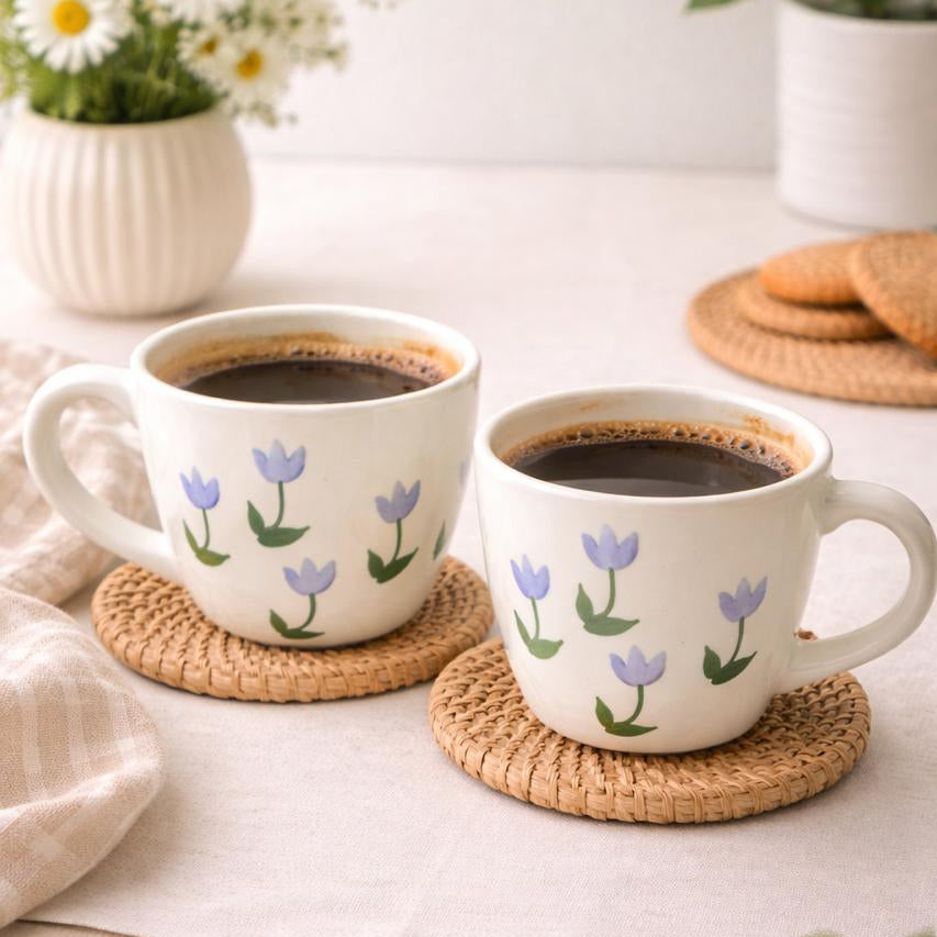 Two white mugs with floral designs on a table with a white background