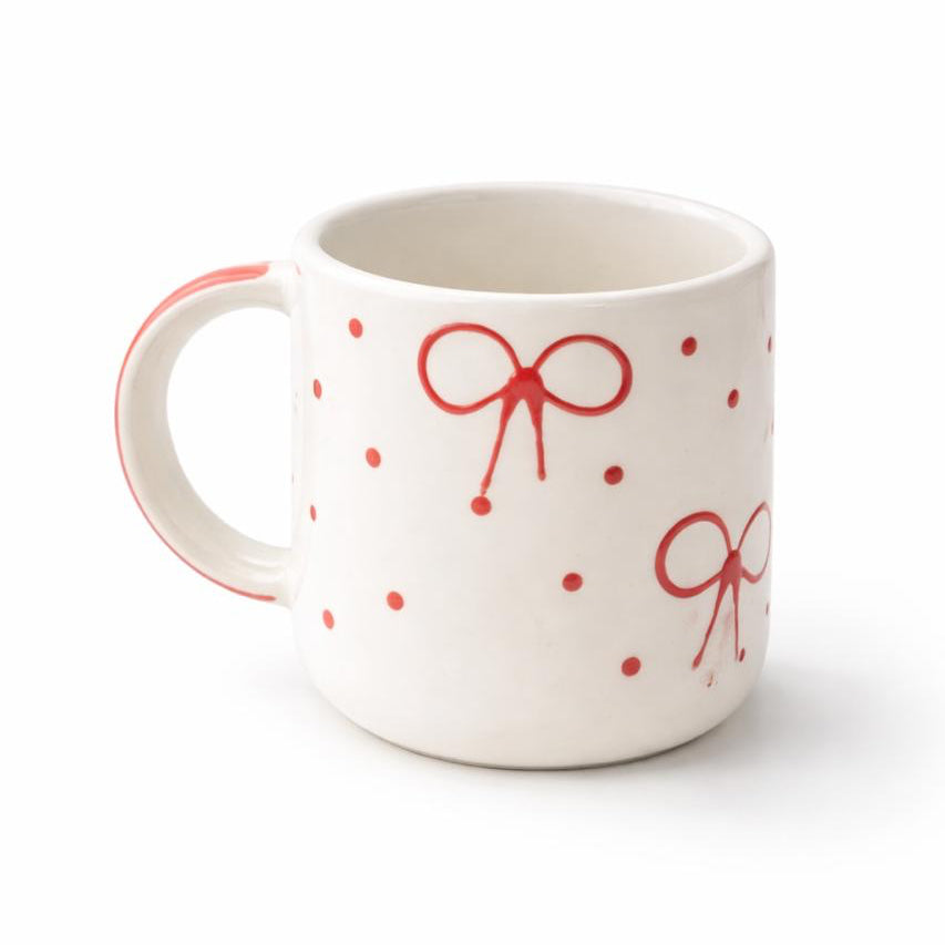 White mug with red bow designs on a white background