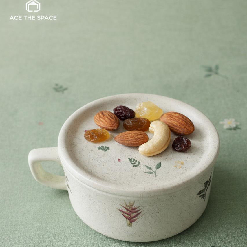 White ceramic cup with dried fruits on a light green fabric background