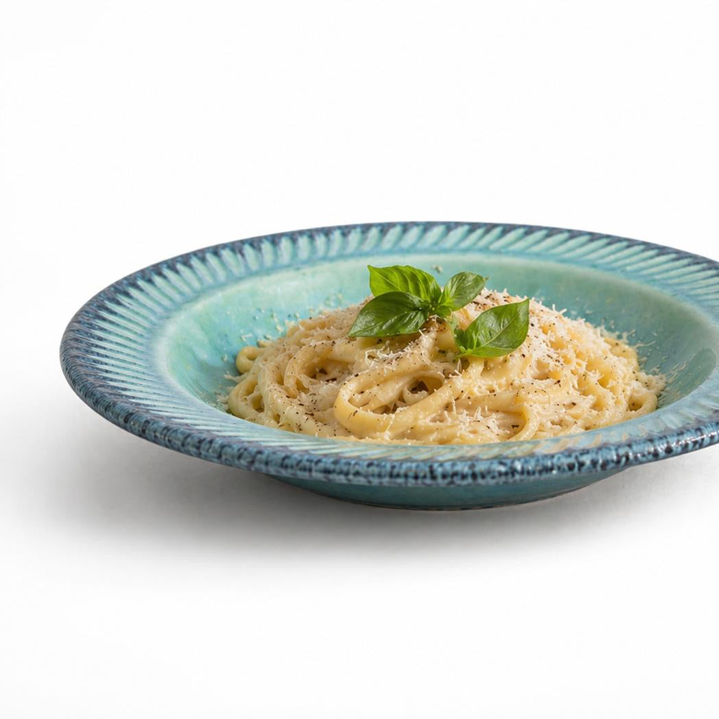 Pasta dish with basil leaves on a blue ceramic plate against a white background