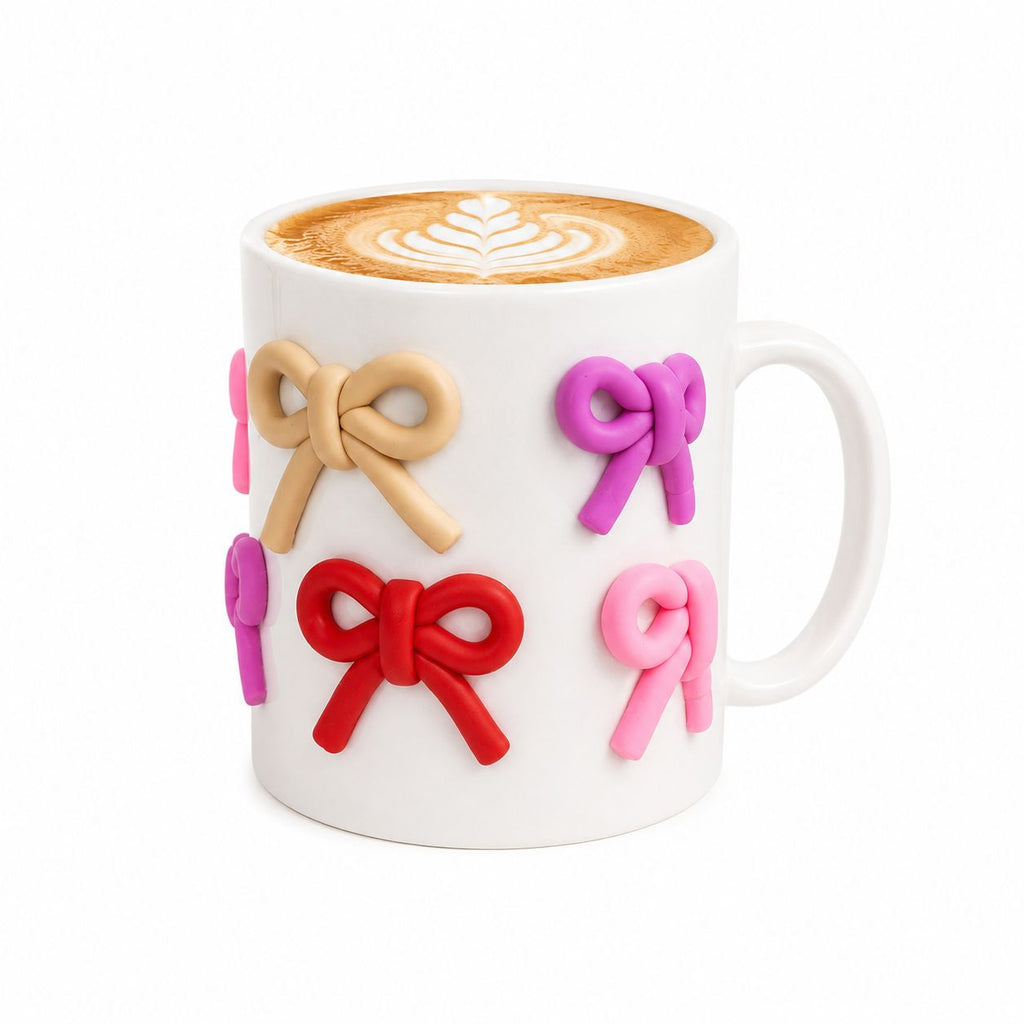 White mug with colorful bow designs holding a cup of coffee.