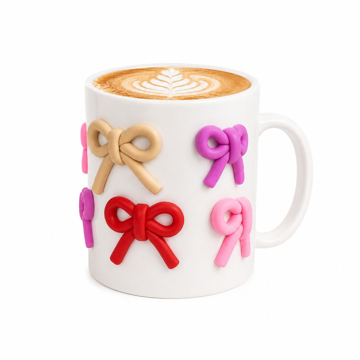 White mug with colorful bow designs holding a cup of coffee.