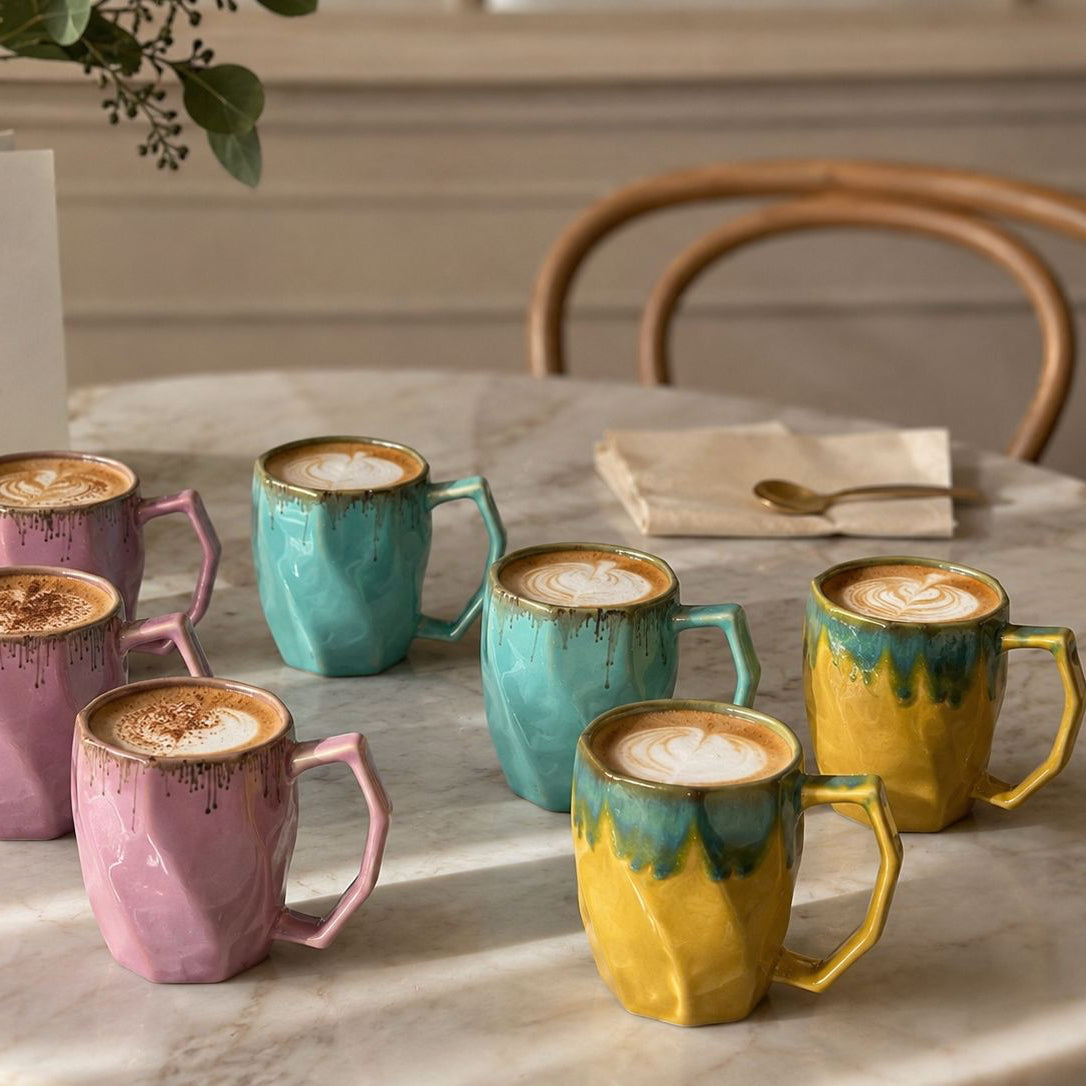 Set of colorful mugs with a drink on a marble table.