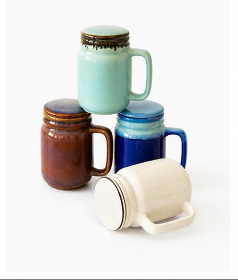 Collection of ceramic mugs with lids in various colors on a white background