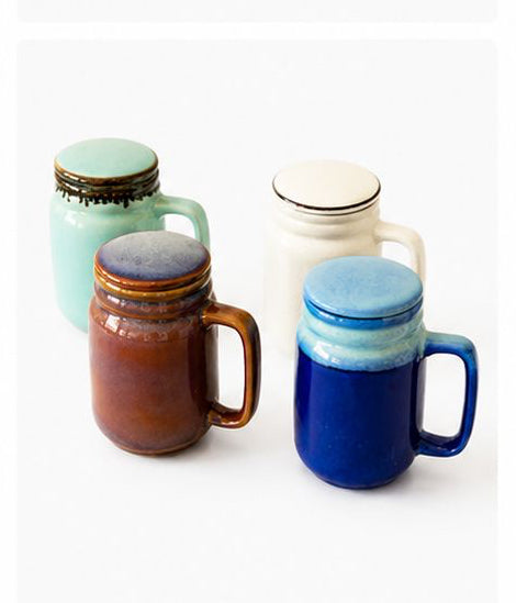Collection of ceramic mugs with lids in various colors on a white background