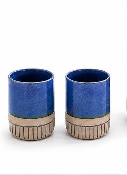 Collection of ceramic mugs and pitchers in red, blue, and pink on a white background
