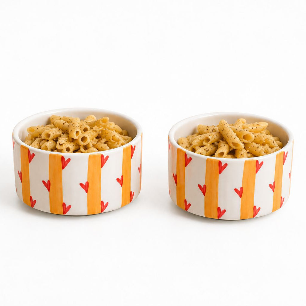 Two bowls of macaroni and cheese with a colorful pattern on a white background