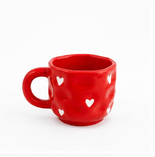 Set of six colorful mugs with heart patterns on a white background