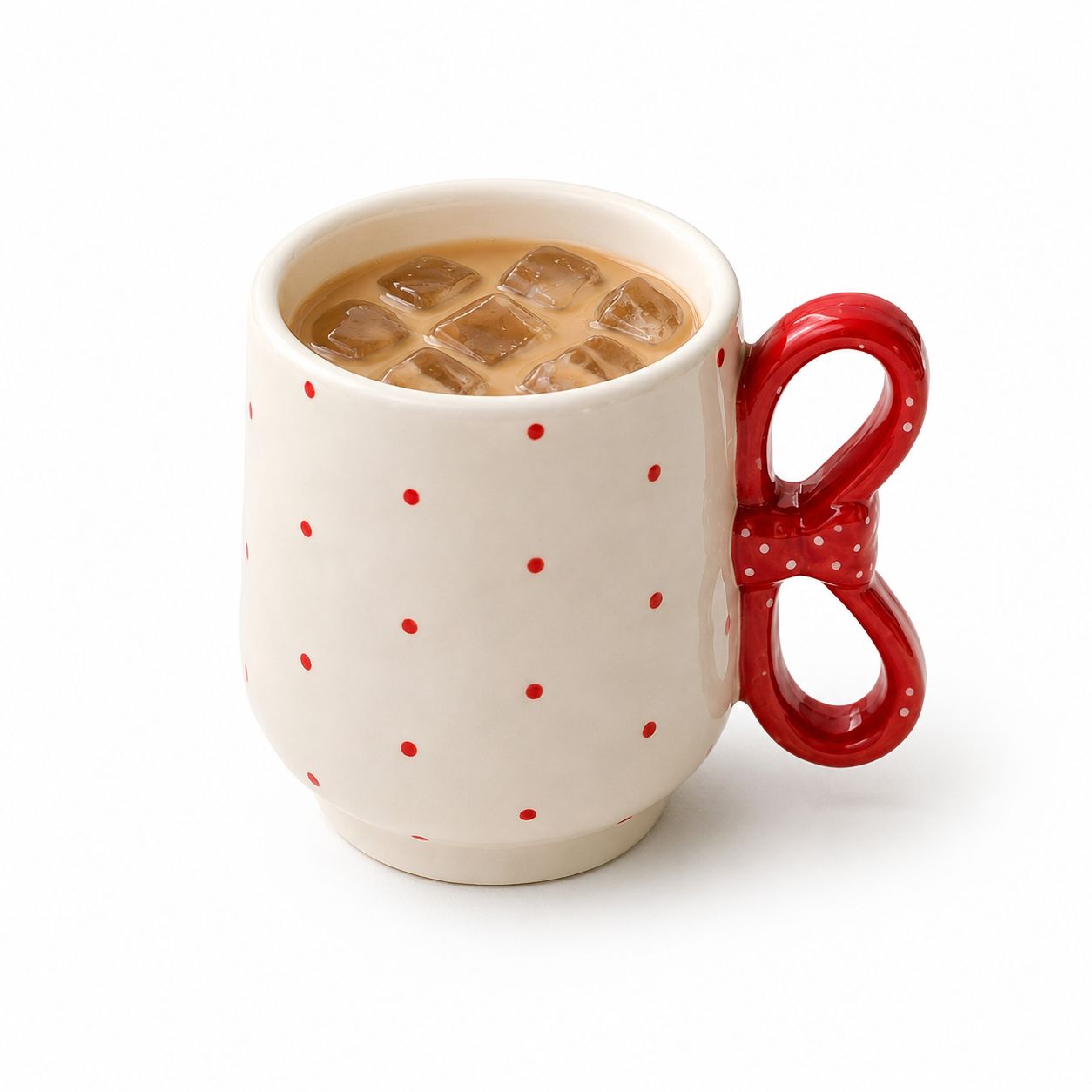 Mug with red handle and red polka dots filled with iced coffee on a white background