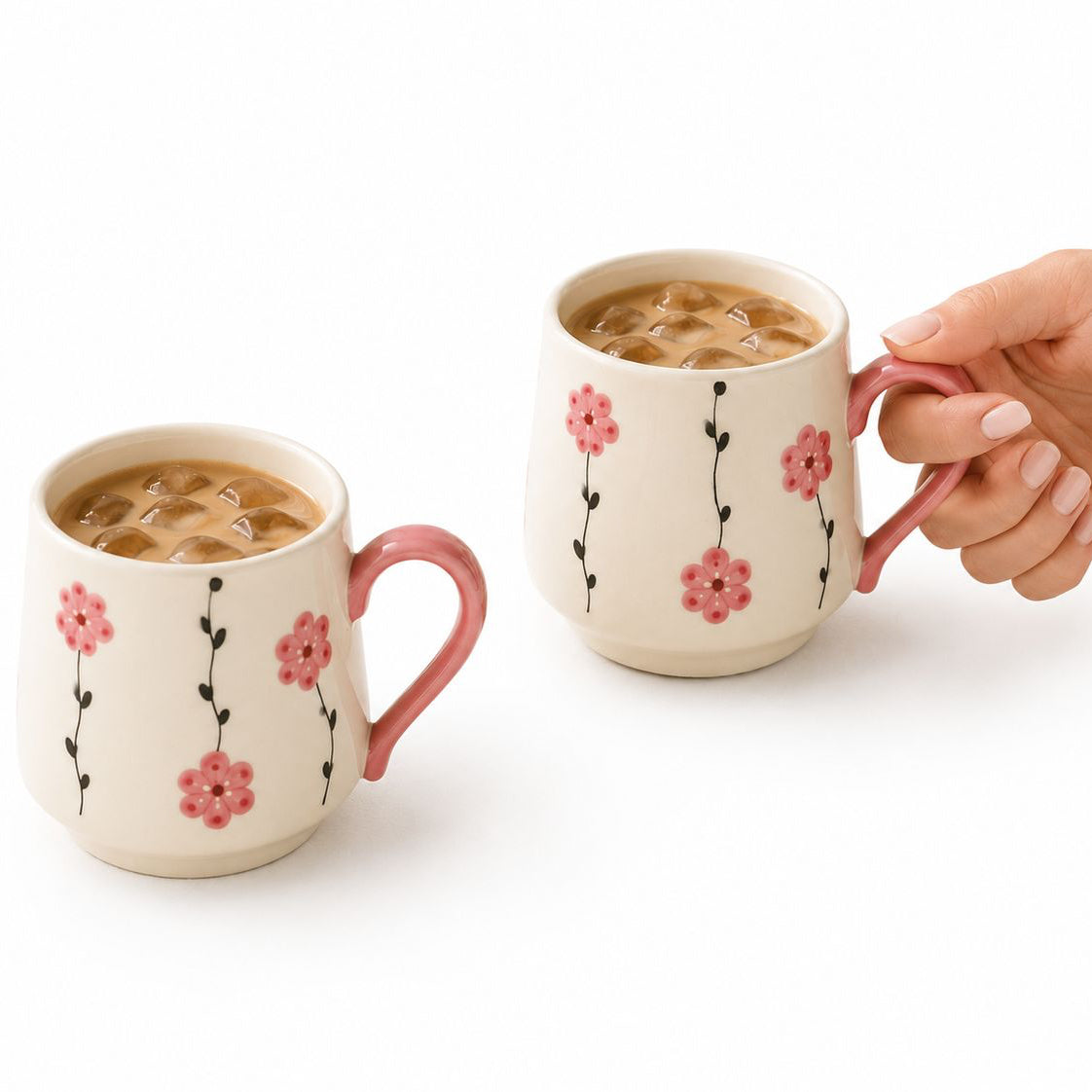 Two floral-patterned mugs with a hand holding one, on a white background