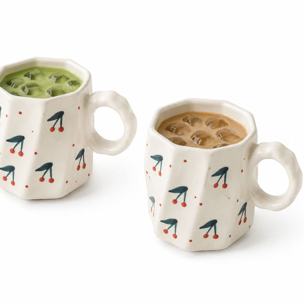 Two ceramic mugs with geometric patterns filled with different beverages on a white background