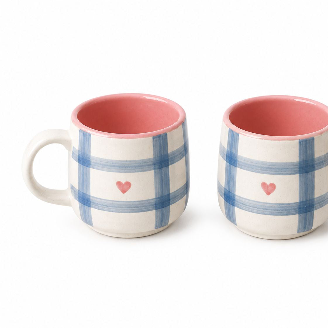 Two ceramic mugs with blue plaid patterns and pink hearts on a white background