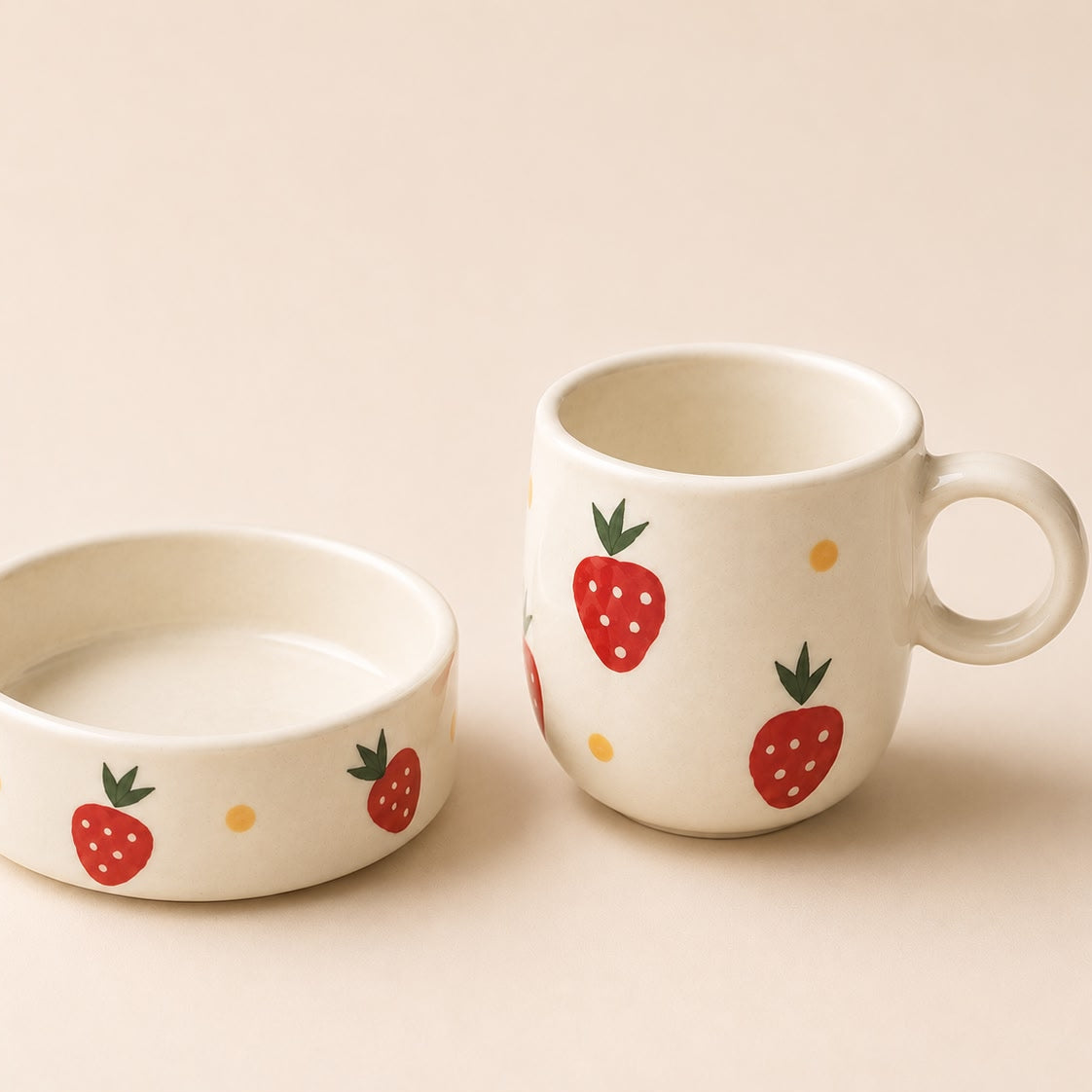 Ceramic mug and bowl set with strawberry design on a beige background