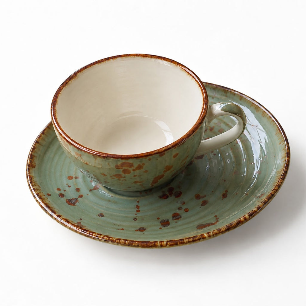 Ceramic cup and saucer with brown speckles on a white background