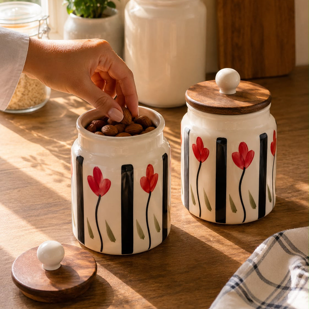 Ceramic jars with floral designs on a wooden surface, one being opened to add almonds.