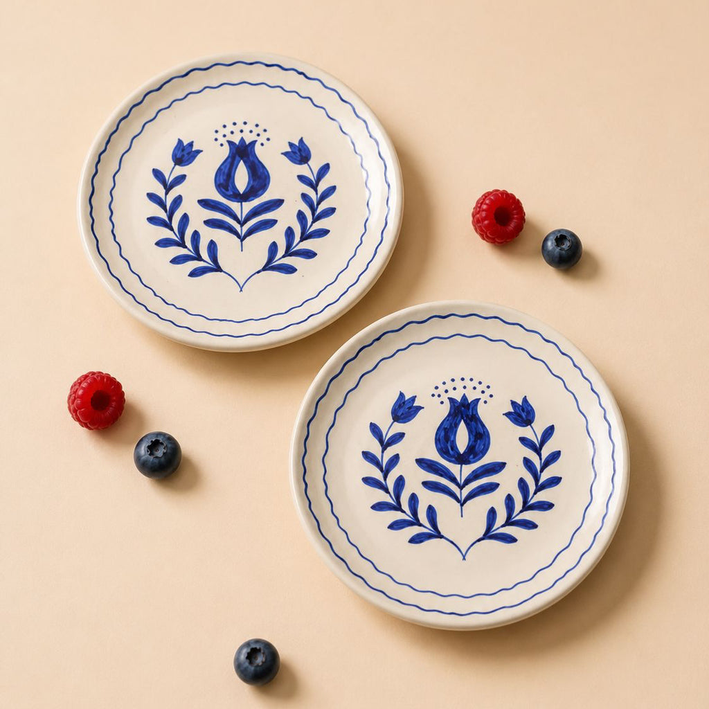 Two white plates with blue floral patterns on a beige background with berries.