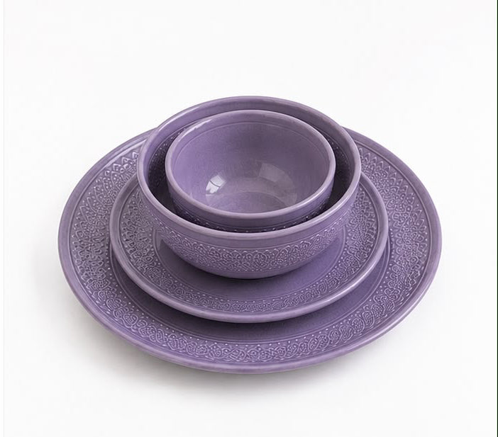 Set of purple ceramic dishes including bowls and plates on a white background