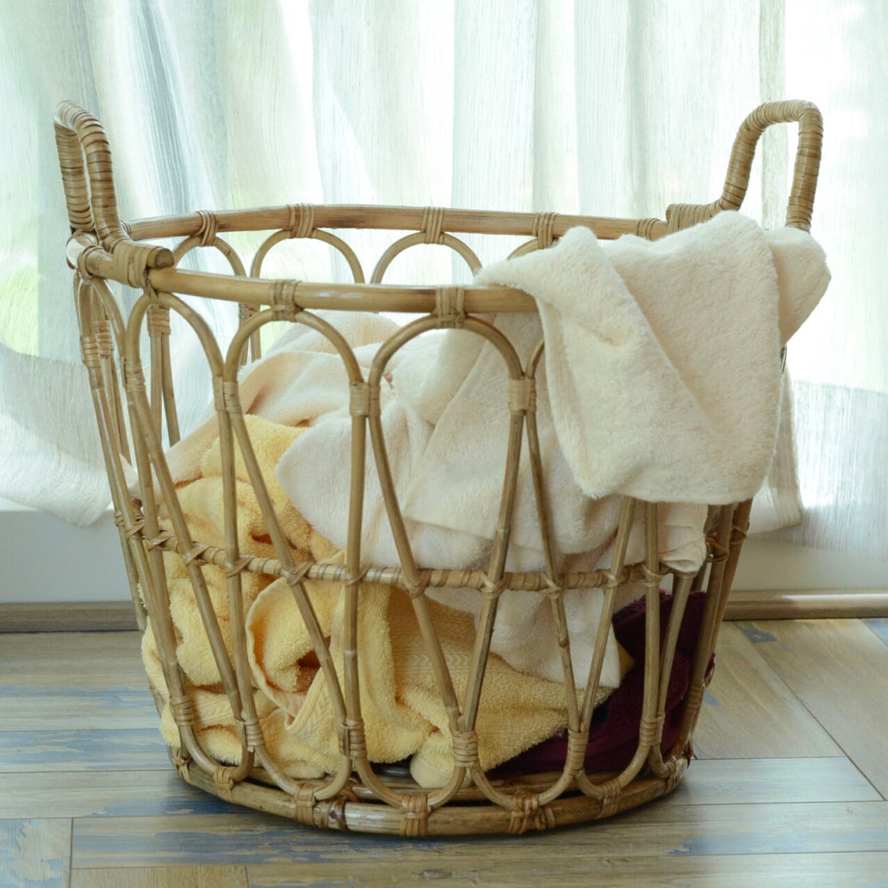 Wicker laundry basket with clothes on a wooden floor